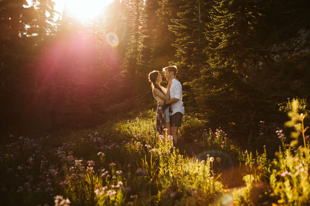 two people stand cuddled in a sun drenched field