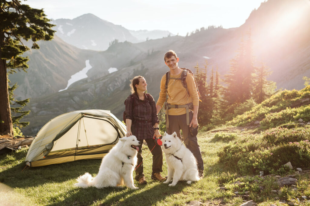 bride and groom pose with their dogs in front of tent